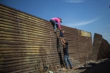 Des migrants grimpent au-dessus d'une clôture à la frontière entre le Mexique et les Etats-Unis, à Tijuana le 25 novembre 2018
