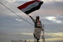 Photo prise le 10 décembre 2017 montrant un Irakien brandissant le drapeau national sur la place Tahrir à Bagdad lors d'une cérémonie célébrant la victoire sur les jihadistes