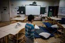 Un enfant prépare son lit installé dans une classe le 10 janvier 2019 à Vaulx-en-Velin