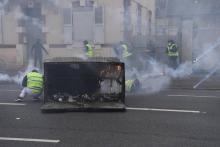 Des "Gilets jaunes" derrière une benne à ordures incendiée lors d'affrontements avec la police, le 12 janvier 2019 à Bourges