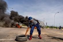Un policier retire un pneu de la chaussée lors d'une manifestation contre la hausse des prix des carburants, le 14 janvier 2019 à Bulawayo