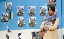 Une Iranienne debout devant un mur placardé de photos du président et alors candidat à la présidentielle, Hassan Rohani, dans une rue de la capitale Téhéran le 17 mai 2017