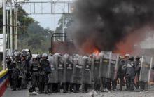 Les forces de sécurité vénézuéliennes se tiennent devant un camion brûlé tandis qu'il tentait de franchir la frontière, le 25 février 2019 sur le pont Francisco de Paula Santander