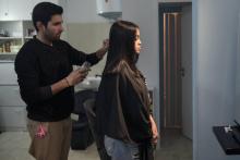 Un réfugié pakistanais Manassif Raza coiffe dans son salon, centre d'Athènes une jeune femme le 23 janvier 2019