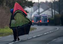 Un migrant porte sa tente sur le dos après l'évacuation d'un camp par la police le 21 février 2019