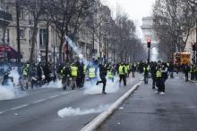Un manifestant renvoit une grenade lacrymogène lors de la 13e manifestation des gilets jaunes à Paris le 9 février 2019