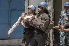 Des gendarmes transportent un policier en civil blessé lors de la dispersion d'une manifestation de l'opposition à Moroni, le 25 mars 2019
