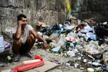 Un homme attend de trouver un peu de nourriture à côté d'un dépôt d'ordures, le 14 mars 2019 dans le quartier de Las Minas, à Caracas