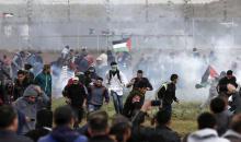 Des Palestiniens courent pour éviter des gaz lacrymogènes tirés par l'armée israélienne près de la frontière entre la bande de Gaza et Israël, le 30 mars 2018