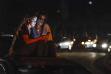 Deux femmes utilisent un téléphone portable sur l'autoroute Francisco Fajardo de Caracas grâce à la proximité de relais téléphoniques, au cours de la panne électrique, le 9 mars 2019