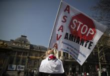 Un manifestant tient une banderole "Stop amiante" devant le Palais de Justice de Paris, le 22 mars 2019