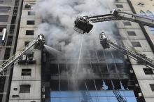 Des pompiers dans des nacelles de grandes échelles tentent d'éteindre l'incendie d'un immeuble de bureaux à Dacca, le 28 amrs 2019 au Bangladesh