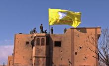 Capture d'écran diffusée le 23 mars 2019 par la télévision kurde Ronahi montrant les Forces démocratiques syriennes (FDS), dominées par les Kurdes, hisser leur drapeau sur un bâtiment de Baghouz, dans