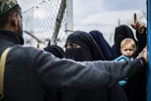Des femmes en niqab noirs parlent avec un membre des Forces démocratiques syriennes (FDS), dans le camp de déplacés d'Al-Hol qui abrite des milliers de personnes affiliées au groupe jihadiste Etat isl