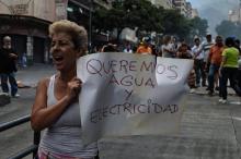 Une femme brandit une affiche "Nous voulons de l'eau et de l'électricité" lors d'une manifestation à Caracas le 31 mars 2019