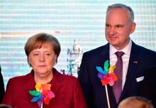 La chancelière allemande Angela Merkel et le président du conseil de gestion d'E.ON SE Johannes Teyssen posent avec des moulins à vent pendant la cérémonie d'inauguration du parc éolien d'Arkona à Sas