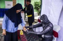 Un fonctionnaire électoral costumé en superhéros dans un bureau de vote de Surabaya le 17 avril 2019