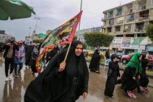 Une femme marche avec une bannière à Bagdad dans le cadre d'un pèlerinage en commémoration de la mort de l'imam Moussa Kazim, le 2 avril 2019