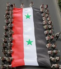 Des soldats syriens portent un drapeau de leur pays à l'occasion de la fête nationale, le 17 avril 2019