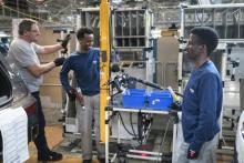 Said Abdelatif (2e g) d'Erythrée et Idriss Nazar, du Soudan travaillent sur une ligne de montage à l'usine PSA de Mulhouse, le 9 avril 2019