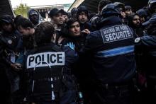 Des policiers tentent de repousser des migrants qui veulent monter à bord d'un bus lors d'une opération d'évacuation d'un campement Porte de la Chapelle dans le nord de Paris, le 4 avril 2019
