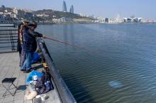 Des pêcheurs au bord de la mer Caspienne à Bakou, où des traces de pétrole sont visibles dans l'eau, le 22 mars 2019