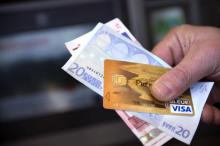 Une personne tient dans sa main des billets de banque et une carte bancaire, le 5 février 2013 à Tours