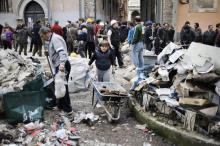 Des habitants nettoient les décombres après le séisme meurtrier qui a frappé la ville médiévale de L'Aquila et sa région, dans le centre de l'Italie, le 6 avril 2010