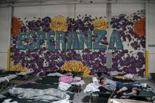 Des migrants originaires d'Amérique centrale sont allongés sur des lits de camp installés sous un graffiti "ESPERANZA" (espoir en espagnol) dans la Maison du réfugié, ouverte à El Paso dans le sud du 