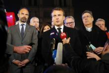 Le Premier ministre Edouard Philippe (G) et le président Emmanuel Macron (C) au pied de Notre Dame après l'incendie qui très gravement endommagé la cathédrale, le 15 avril 2019 à Paris