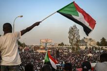 Un manifestant soudanais brandit le brapeau national lors d'un rassemblement devant le QG de l'armée à Khartoum, le 18 avril 2019