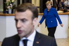 Le président français Emmanuel Macron discute avec des journalistes tandis que passe derrière lui la chancelière allemande Angela Merkel, le 11 avril 2019, à Bruxelles.
