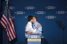 Pete Buttigieg (g), candidat à la Maison Blanche, embrasse son mari Chasten Glezman sur scène après avoir annoncé le lancement de sa campagne, le 14 avril 2019 à South Bend, dans l'Indiana