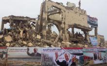 Des combattants yéménites loyaux au pouvoir soutenu militairement par l'Arabie saoudite au milieu des débris d'un immeuble regardent le lancement des projets d'aide saoudiens dans la ville de Midi dan