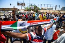 Un manifestant soudanais brandit une banderole représentant le drapeau national au sit-in devant le QG de l'armée, à Khartoum, le 14 mai 2019