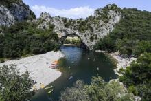 Des touristes en canoës et sur les berges de l'Ardèche au "Pont d'Arc", dans les gorges de l'Ardèche, le 1er août 2018