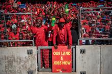 Des Sud-Africains du parti EFF participent au dernier meeting du parti le 5 mai 2019 devant une affiche o l'on peut lire: "notre terre et des emplois maintenant"