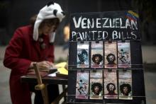 L'artiste et migrante vénézuélienne Paula Villamizar peint avec son compagnon Javier Caballos des portraits de personnalités sur des bolivars, le 3 mai 2019 dans une rue de Bogota, en Colombie