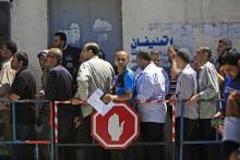 Des Palestiniens font la queue devant un bureau de poste dans la ville de Gaza le 13 mai 2019 pour recevoir une aide en liquide, faisant partie des millions de dollars distribués par le Qatar pour aid