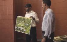 Valentino Dixon (g) montre ses dessins de terrains de golf à des détenus dans une prison de Washington, le 2 mai 2019 aux côtés du professeur Marc Howard de l'université de Georgetown