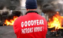 Un employé de l'usine Goodyear d'Amiens-Nord regarde des pneus brûler devant l'entrée du site, le 18 novembre 2013