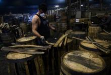 Un employé inspecte l'intérieur de tonneaux usés qui seront remis à neuf et envoyés à l'étranger pour être utilisés pour le whisky, le 12 avril 2019 à la distillerie Kelvin Cooperage à Louisville, dan