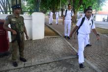 Des jeunes se rendent à l'école à Colombo le 6 mai 2019, sous la surveillance des forces de l'ordre, à la réouverture des écoles fermées après les attentats qui ont fait plus de 250 morts au Sri Lanka