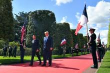 French President Emmanuel Macron (L) and US President Donald Trump walk on the red carpet during a French-US ceremony at the Normandy American Cemetery and Memorial in Colleville-sur-Mer, Normandy, no
