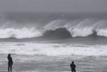 Des personnes observent les vagues sur la plage de El Porto en Californie alors que de forts orages 