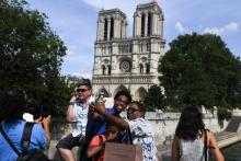 Des touristes devant Notre-Dame de Paris le 13 juillet 2019