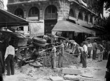 Des Parisiens érigent une barricade avec un camion retourné au coin de la rue de la Huchette et de la place Saint-Michel, en août 1944 à Paris
