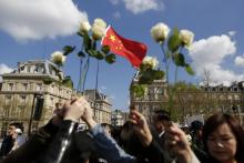 Des manifestants brandissent des roses et un drapeau chinois lors d'un rassemblement à Paris après la mort de Liu Shaoyao, le 26 mars 2017