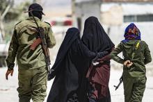 Des gardes armés accompagnent deux femmes de jihadistes dans le camp de Al-Hol, dans le nord-est de la Syrie, le 23 juillet 2019
