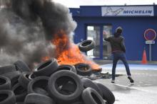 Un employé lance un pneu dans un feu après l'annonce de la fermeture de l'usine Michelin de La Roche-sur-Yon, le 10 octobre 2019